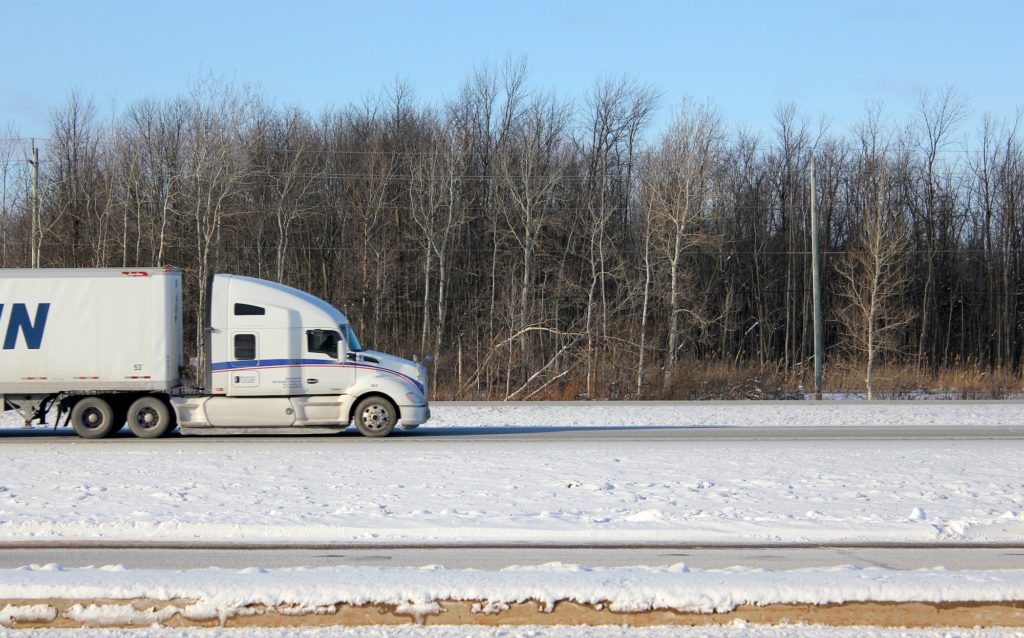 Semi trailer truck transporting a speedy load out on the open road in winter.