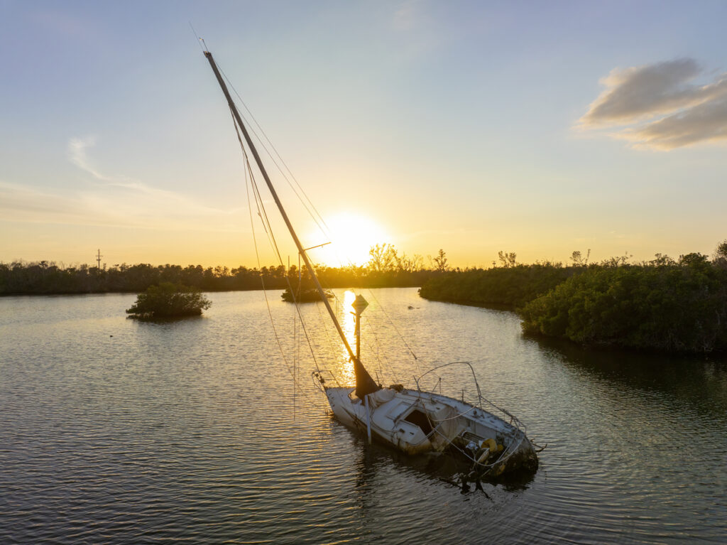Aerial view of sunken sailboat on shallow bay waters after hurricane in Manasota, Florida.
