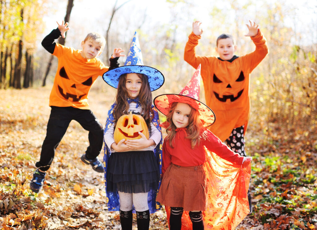 a group of children - boys and girls in bright halloween costumes of pumpkins and witches with a pumpkin in their hands celebrate Halloween and having fun.