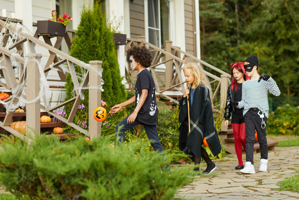 Group of children trick or treating on Halloween walking door to door